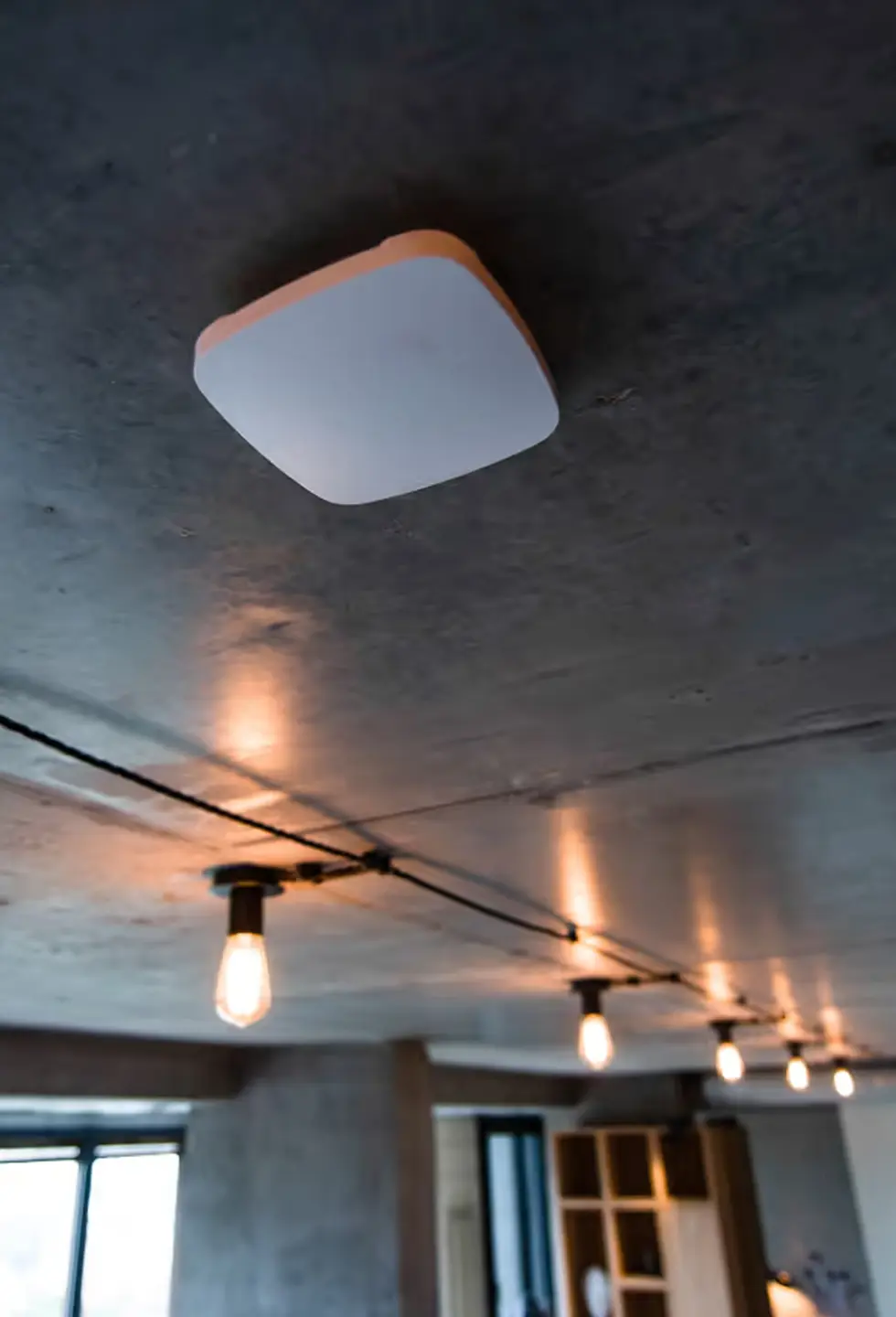 An Ajax fire detector mounted on a concrete ceiling